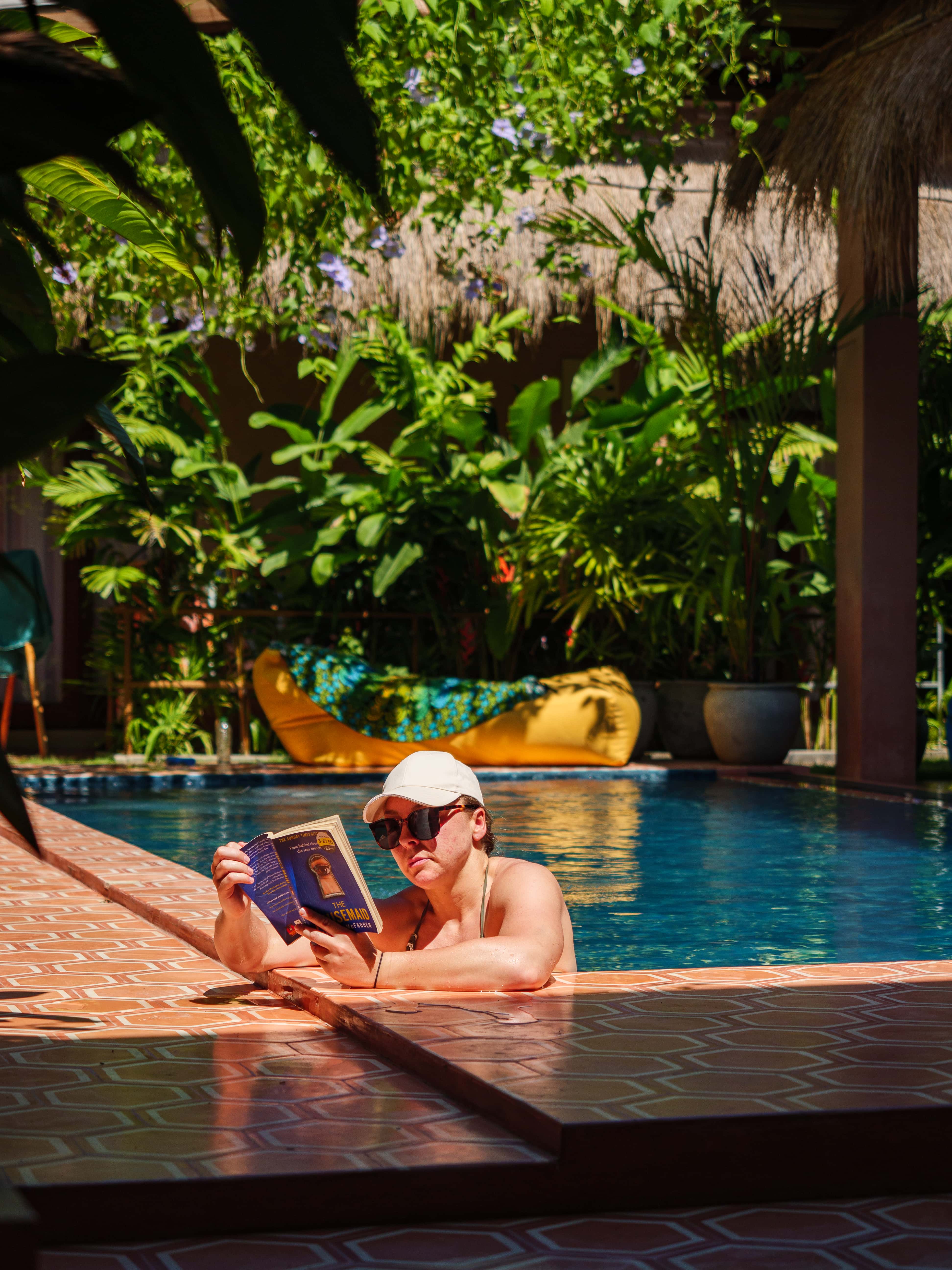 Guest reading a book in the outdoor swimming pool surrounded by tropical gardens at Pine and Palm in Arugam Bay