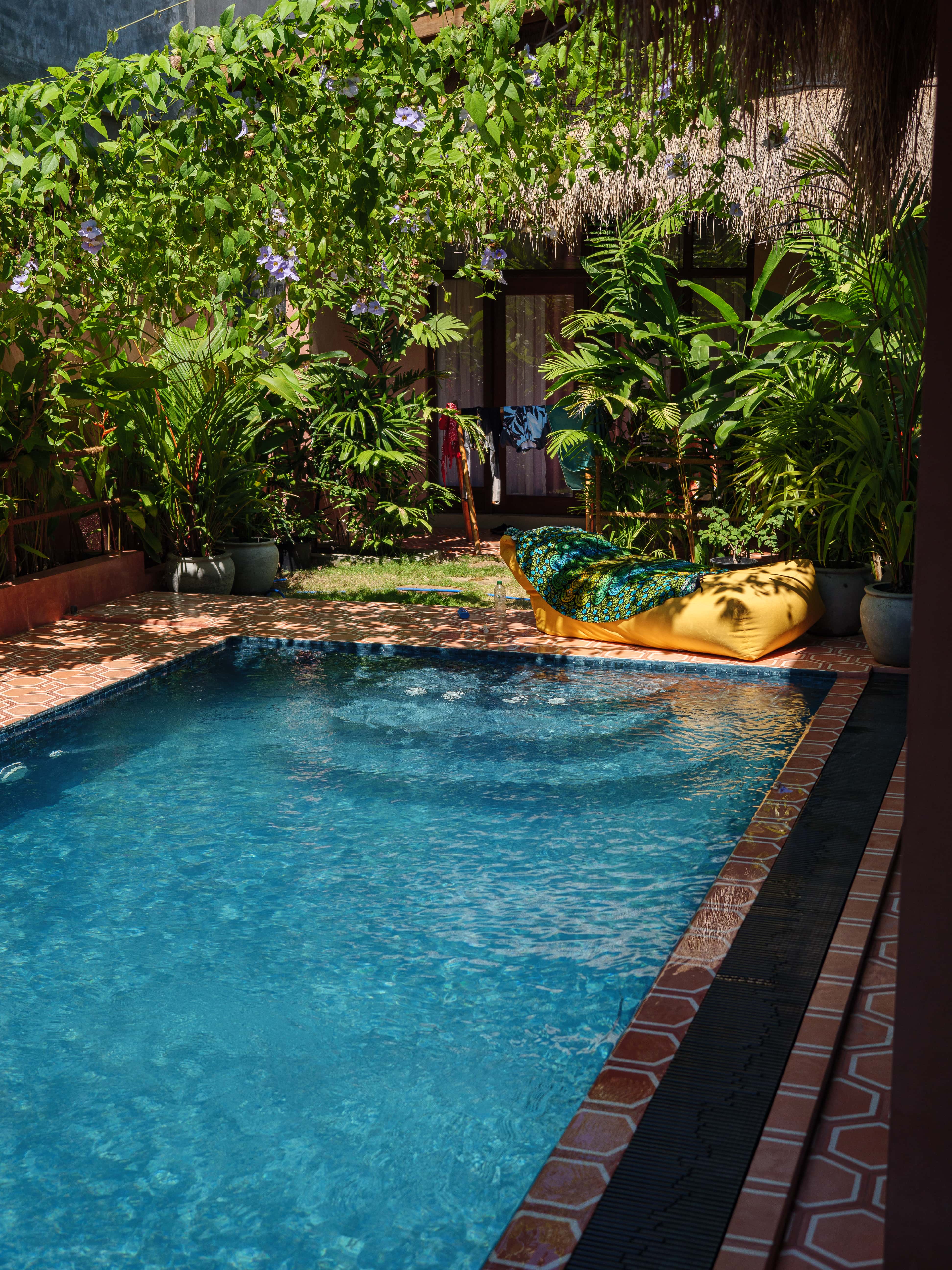 Outdoor swimming pool with yellow bean bag lounge chair and lush tropical gardens at Pine and Palm in Arugam Bay
