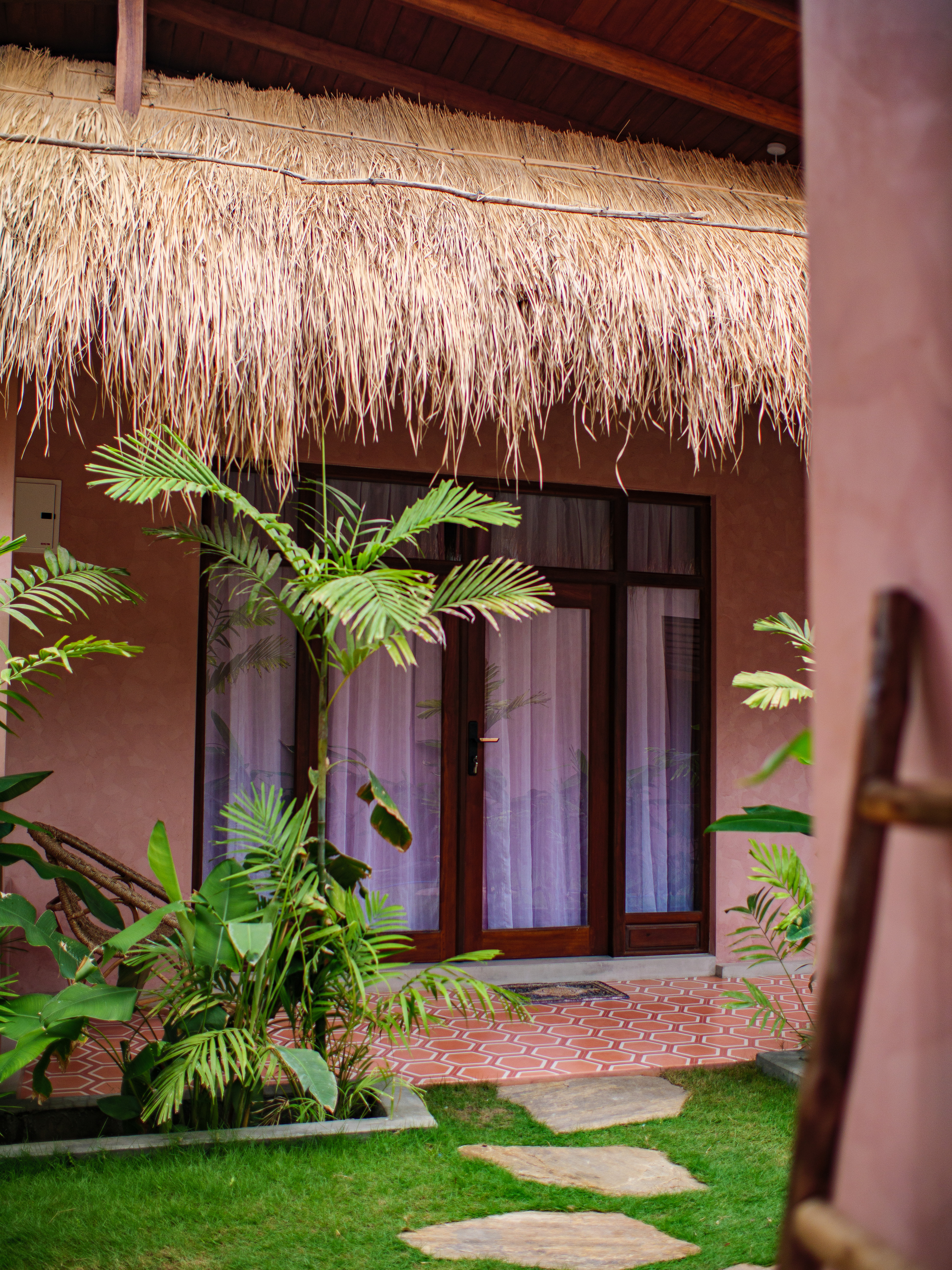 Boutique double room exterior with thatched roof, private terrace, and tropical garden path at Pine and Palm in Arugam Bay