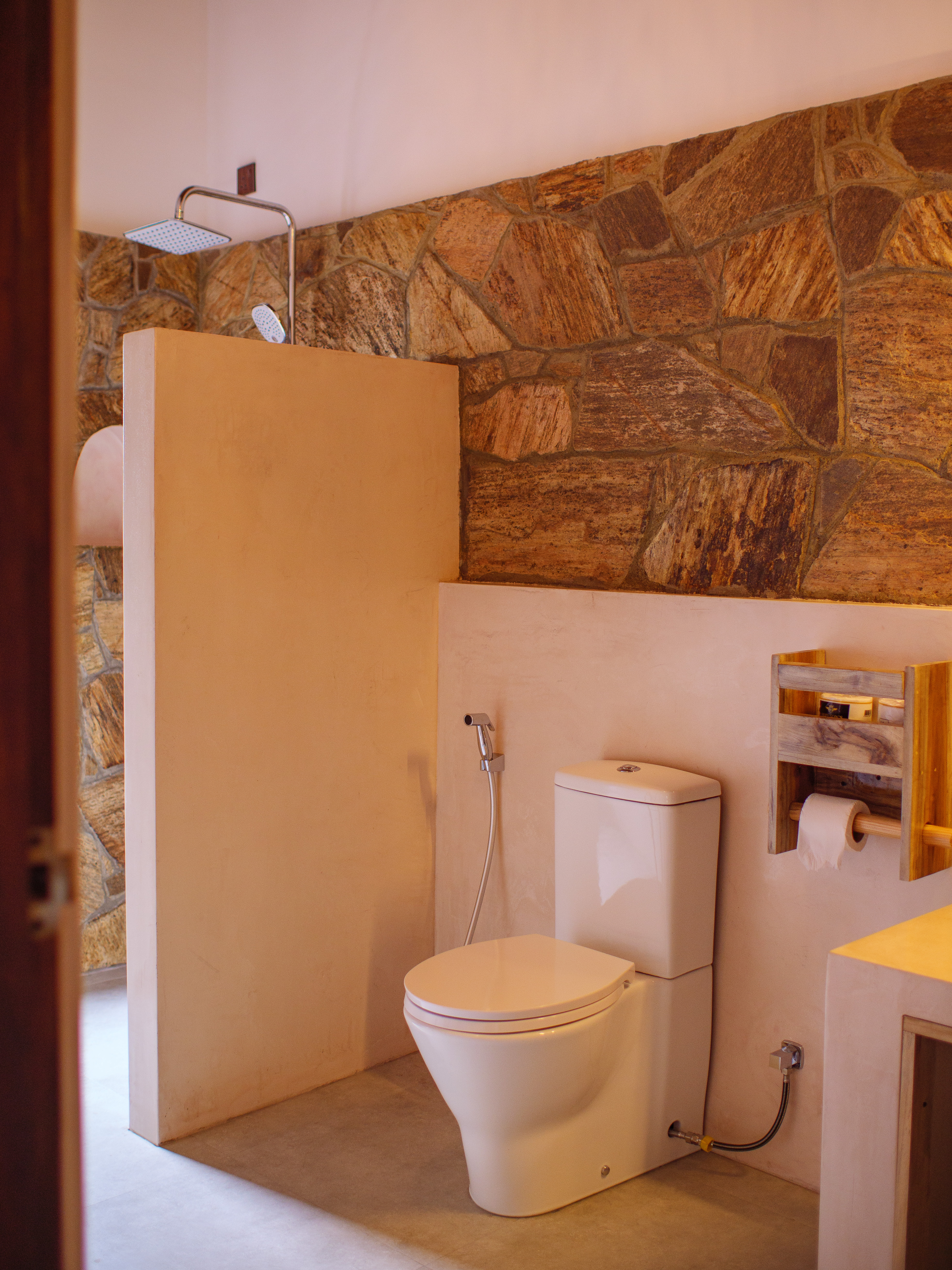 Modern boutique bathroom with a natural stone wall in a double room at Pine and Palm, Arugam Bay.
