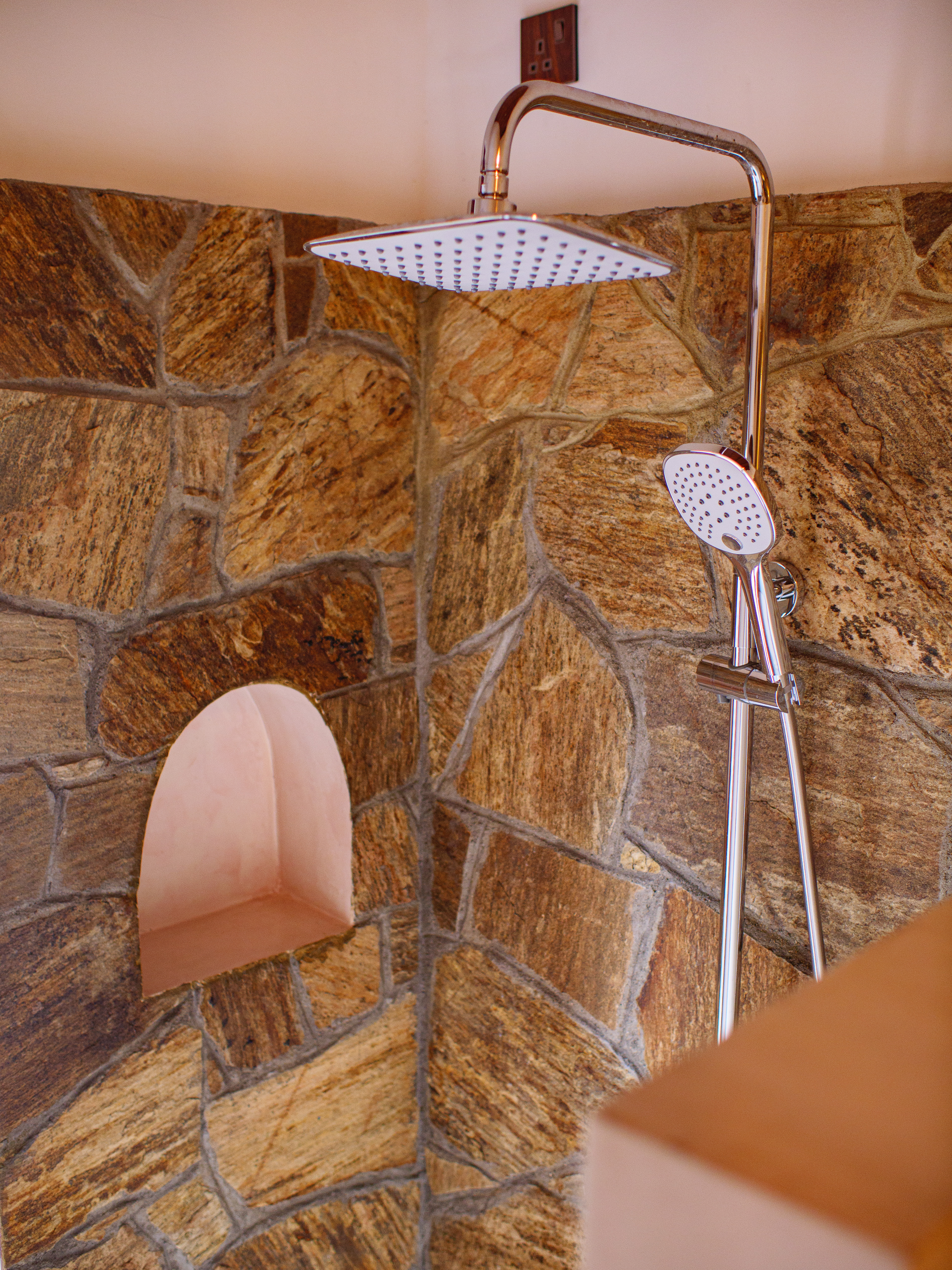 Modern rain shower with a natural stone wall in a boutique double room at Pine and Palm, Arugam Bay.