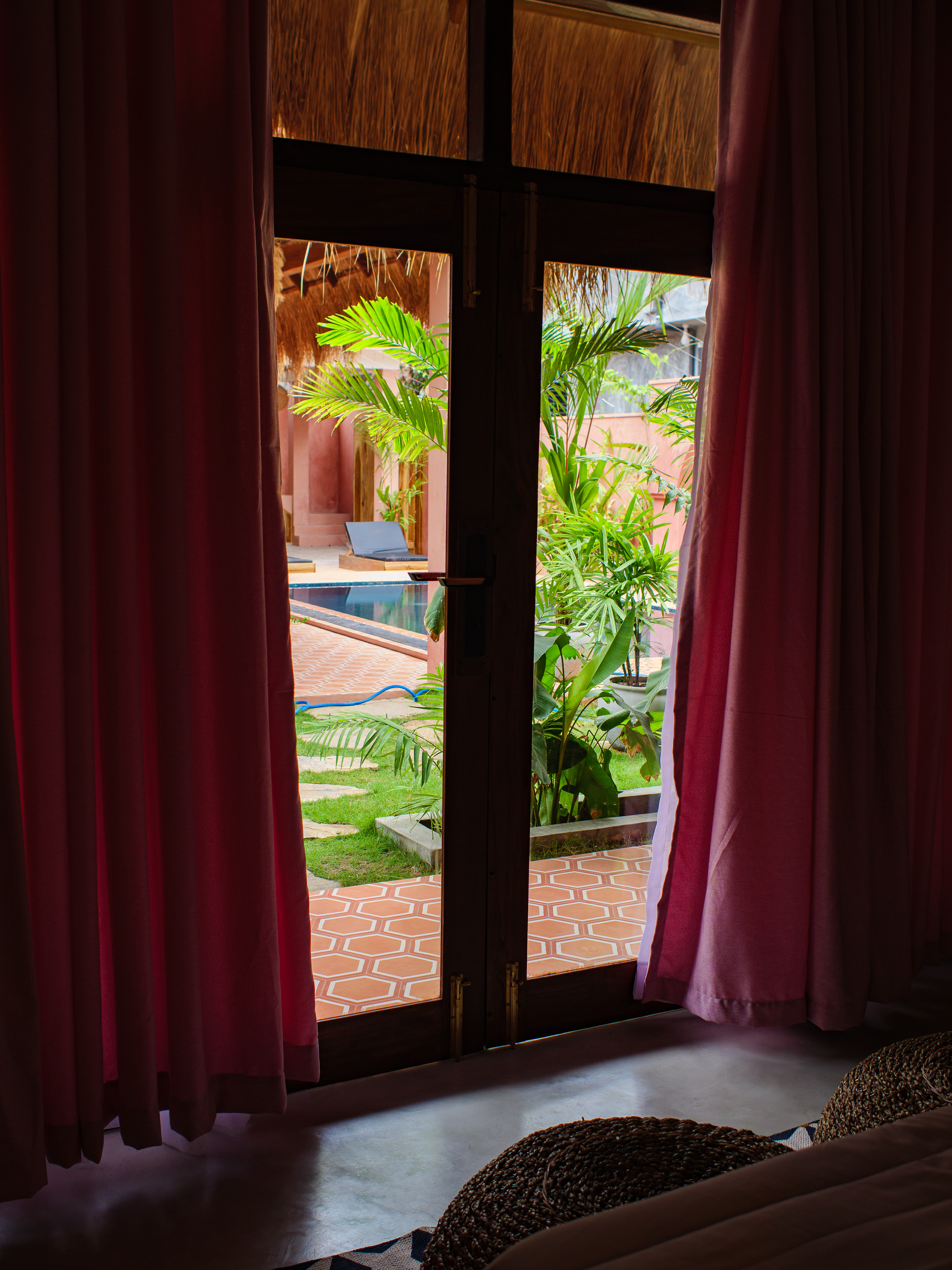 Garden and pool view from double room doorway with pink curtains — Pine & Palm, Arugam Bay