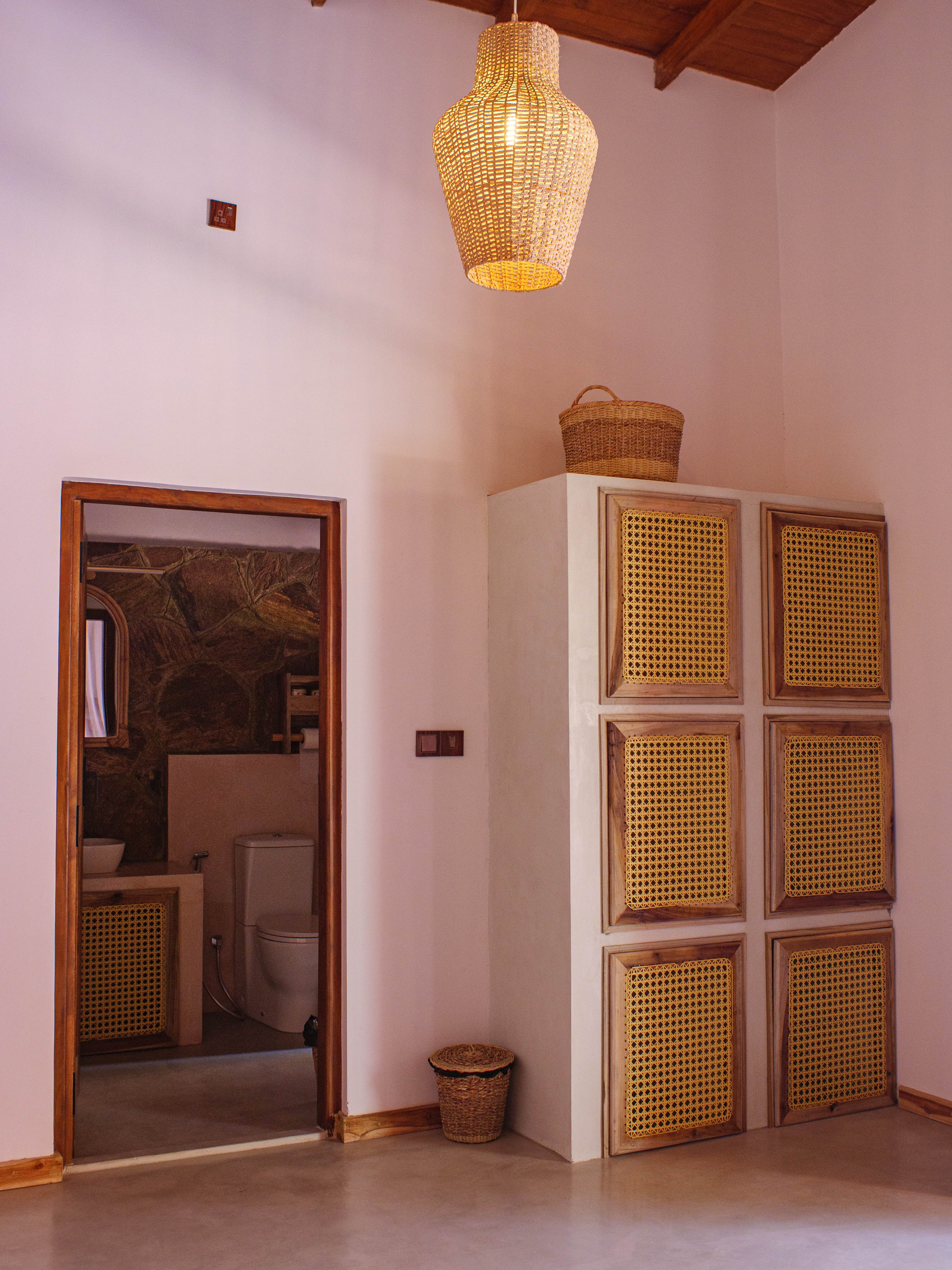 Boutique double room interior showing a woven rattan wardrobe and ensuite bathroom at Pine and Palm in Arugam Bay