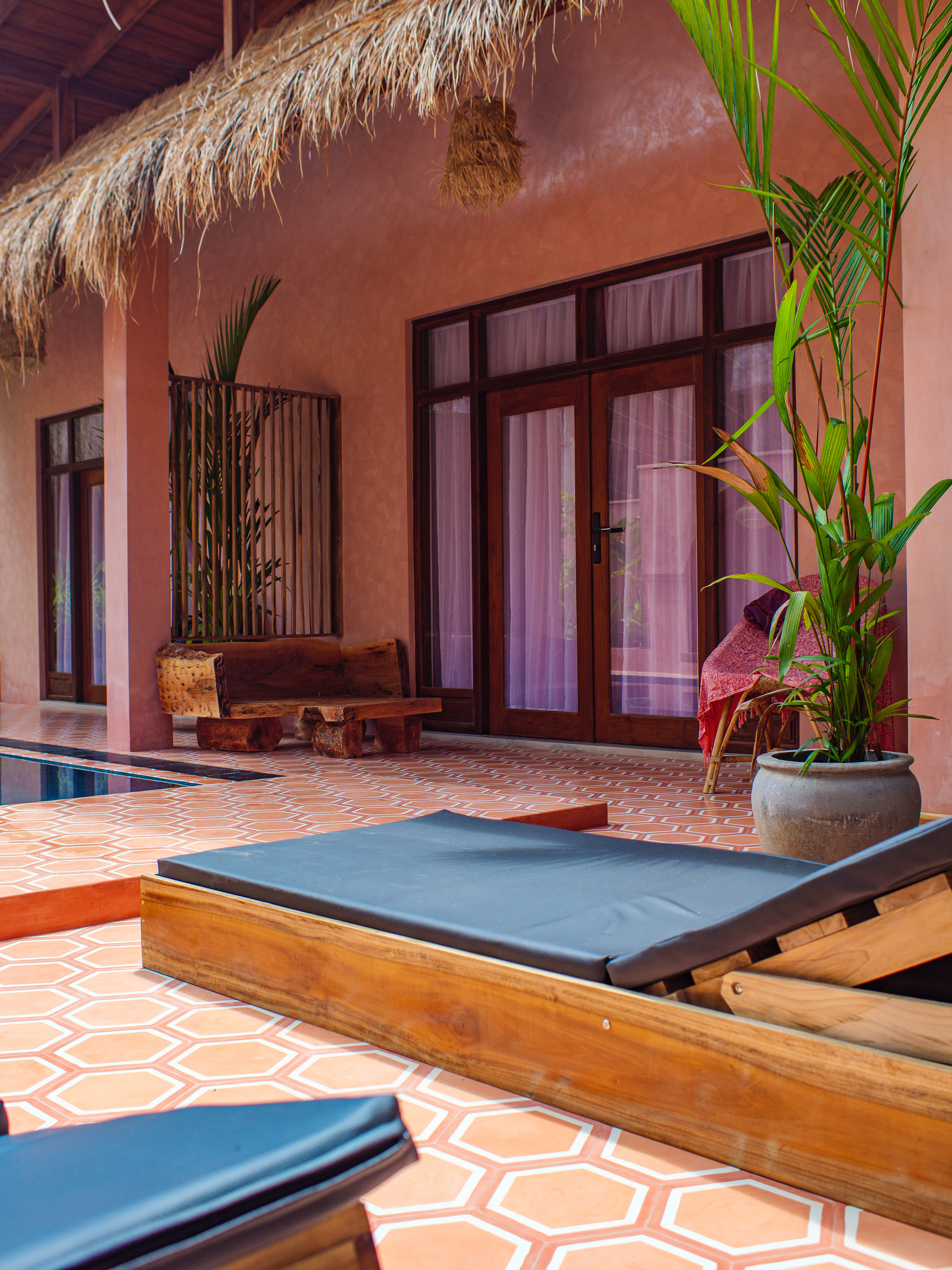 Boutique double room patio with a rustic log bench next to the swimming pool at Pine and Palm in Arugam Bay